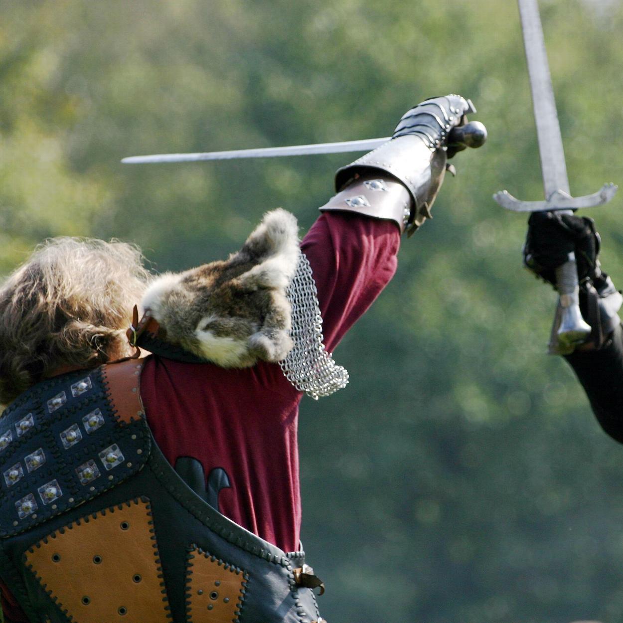 People LARPing fighting with swords in field